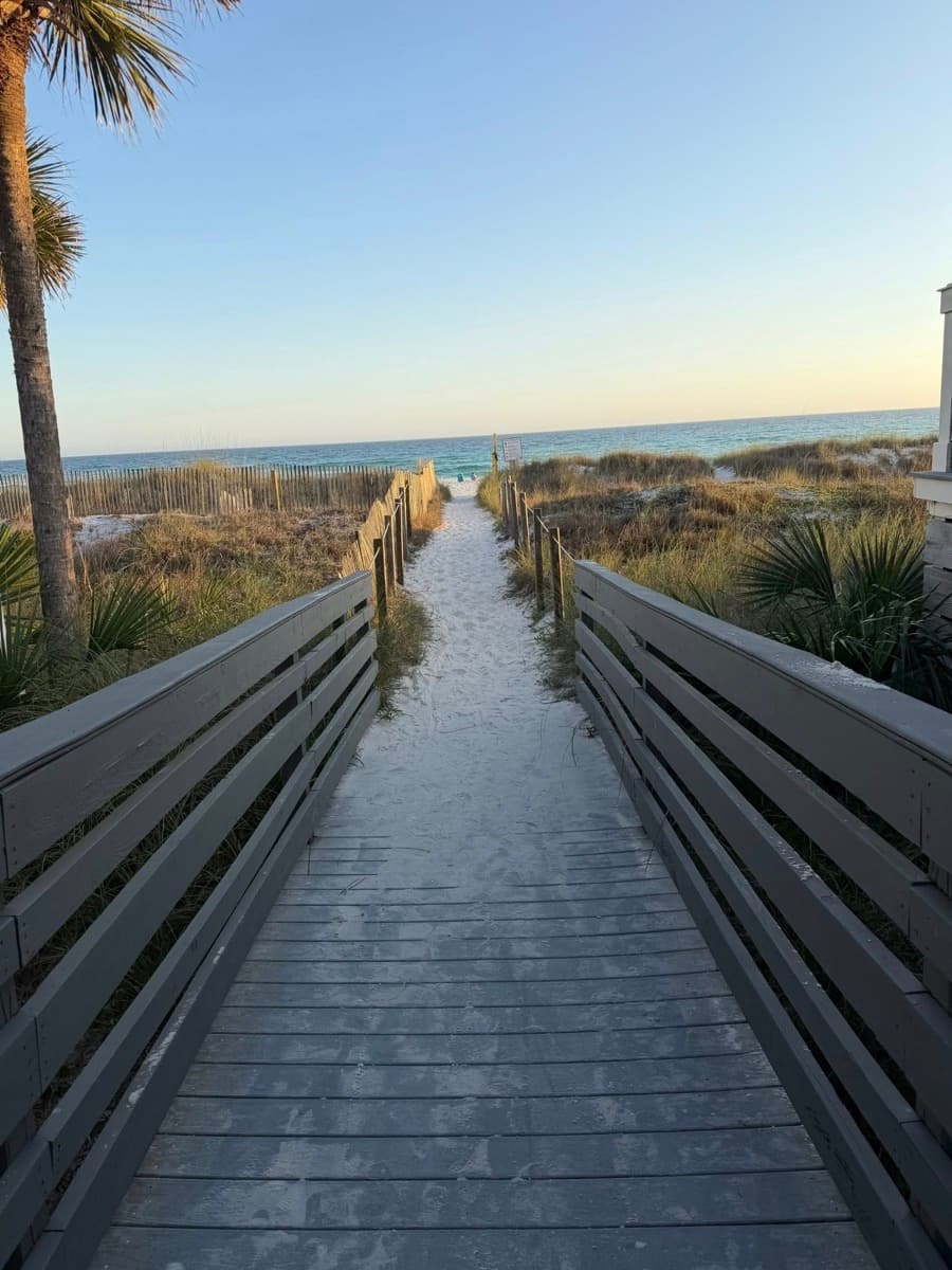 A sandy boardwalk leading down to the Gulf at golden hour
