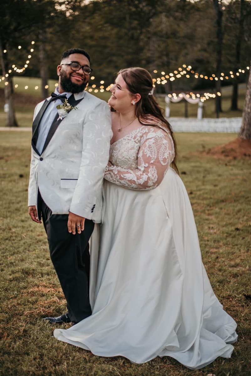 Julianna and her husband on their wedding day, glowing beneath string lights at dusk